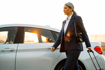 Grey woman walking with suitcase on parking outdoors