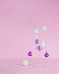 Christmas baubles coming down in glass.Ornaments vivid violet and snowy white on a pink background.New Year holidays concept