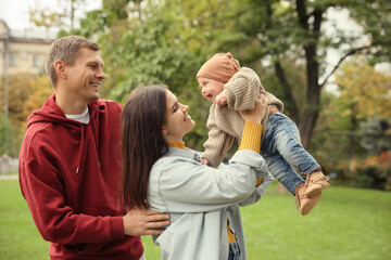 Happy parents with their adorable baby walking in park