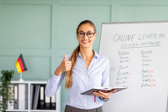 Cheerful female tutor recommending foreign languages school, showing thumb up, giving German lesson and smiling