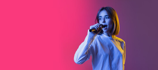 Flyer with pretty girl, teen or student in white casual wear singing isolated on pink-purplr gradient backgroud in neon light