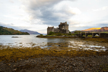 Ancient historic Eilean Donan Castle in the Western Highlands of Scotland under a cloudy sunset sky