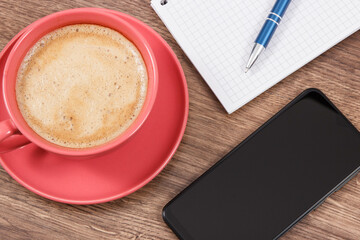 Mobile phone, coffee with milk and notepad for writing notes. Work or relaxation