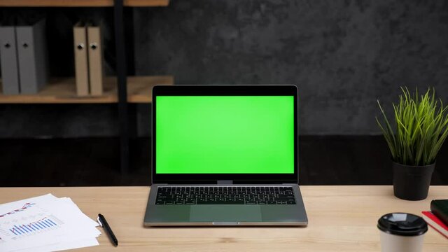 Modern laptop computer display with mock up chroma key green screen standing on table working office business workplace
