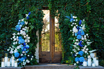 Wedding arch for the ceremony, decorated with fresh white roses, blue orchids and candles. Wedding...