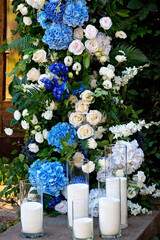 Elements of wedding decor, decorated with fresh white roses, blue orchids and candles. Wedding arch. Soft selective focus.