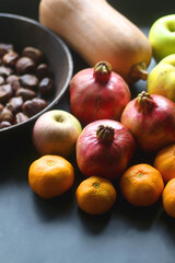 Pan with chestnuts, butternut squash and various fruit on dark background. Selective focus.