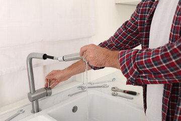 Man repairing water tap in kitchen, closeup