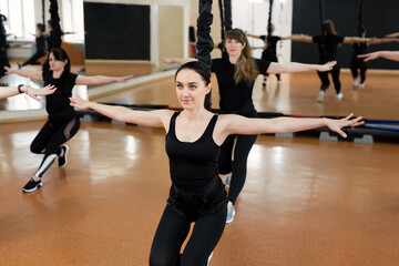 Group of active sports girls in black sportswear are engaged in budgie fitness in the gym. Bungee jumping in the gym