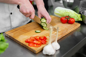 Chef in the kitchen cuts fresh and delicious vegetables for a vegetable salad