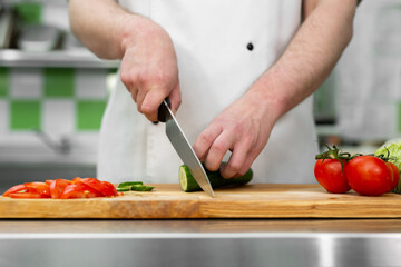 Chef in the kitchen cuts fresh and delicious vegetables for a vegetable salad
