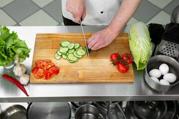Chef in the kitchen cuts fresh and delicious vegetables for a vegetable salad