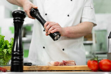 Chef pours salt on beef meat with salt shaker Barbecue