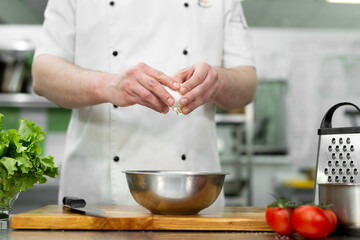 Cook breaks an egg. Egg yolk falling into the bowl