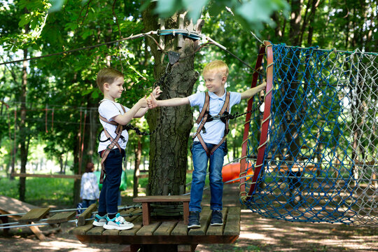 Two little friends say hello while passing the tests in the rope park. - Powered by Adobe