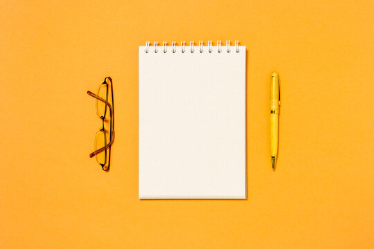 Top view of blank spiral notebook, pen and glasses