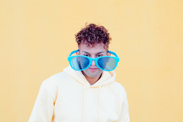 Funny picture : Latin guy with big glasses looking at camera with yellow background