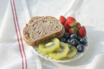 Fresh raw organic berries and exotic fruits in round glass plate on wooden table. cabbage,,kiwi, strawberry.