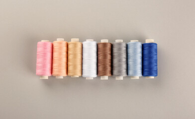 Different colorful sewing threads on light grey background, flat lay
