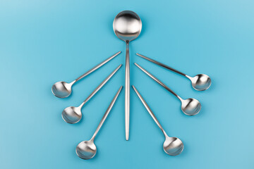 Clean empty  big table spoon and small spoons on blue background, top view. Space for text