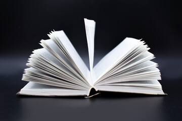 an open old book on a black background. The concept of education and development