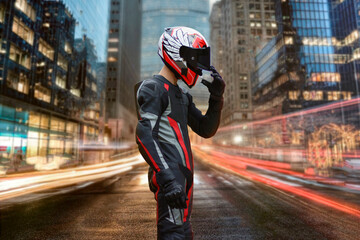 A motorcyclist in full gear and helmet stands in the middle of the street. Night city