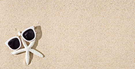 Fototapeta na wymiar White Starfish and sunglasses on natural sand background with shadows, copy space