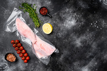 Perch frozen fish meat pack , with herbs, on black dark stone table background, top view flat lay,...