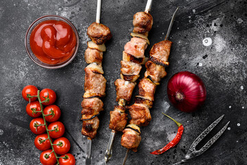 Kebabs grilled meat skewers, shish kebab, on black dark stone table background, top view flat lay