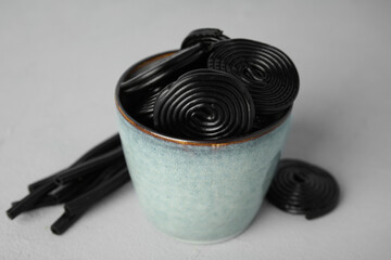 Tasty black liquorice candies on grey table, closeup