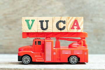Fire ladder truck hold letter block in word VUCA (abbreviation of Volatility, uncertainty,...
