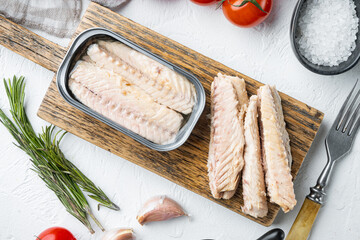 Canned Mackerel Fillets in Tin, on wooden cutting board, on white background with herbs and...