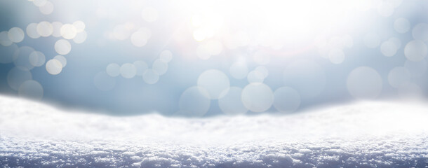 A cold winter snow landscape with sunny sky and sparkling bokeh background for a traditional Christmas scene.