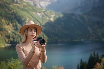 Photographer tourist traveler standing on green top on mountain holding in hands digital photo...
