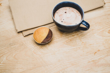 Fototapeta na wymiar cup with hot chocolate milk and delicious cupcake on a rustic wooden and food paper background