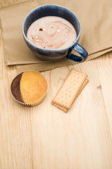 cup with hot chocolate milk a delicious cupcake  and biscuits on a rustic wooden and food paper  background