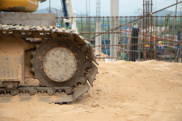 The backhoe's steel track wheels were rusted on iron, parked on the ground in a construction site.