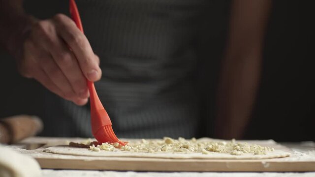 A baker prepares traditional garlic tortillas from dough in a rustic style on a dark background