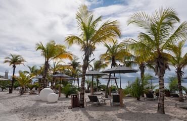 A deserted beach on Bonaire. In the background the dark clouds of the heavy rain shower on the beach are still visible. The raindrops are on the umbrellas, and beach chairs are still wet.