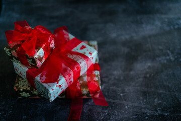 beautifully wrapped gifts on a dark gray background. preparation for the new year and christmas. gift paper and red bows.