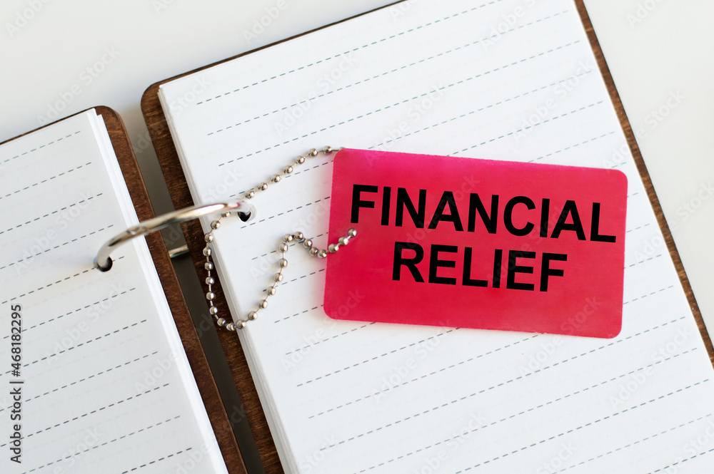 Poster text financial relief text on a red tag that lies on an open notebook on a white background
