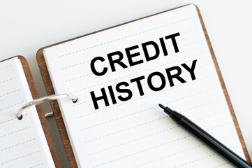 Credit history inscription on an open notebook next to a black marker on a light background, business concept