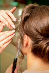 Fototapeta premium Close Up hairdresser stylist makes hairstyle for a young woman in a beauty salon