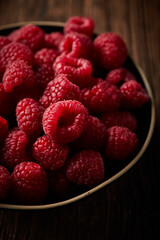 Raspberry in a ceramic bowl over wooden rustic background