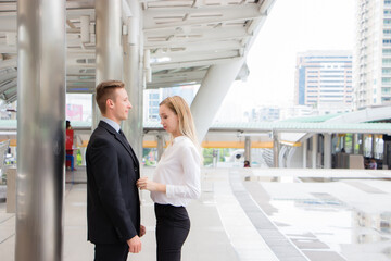 Woman buttoning her suit to a man outdoors.