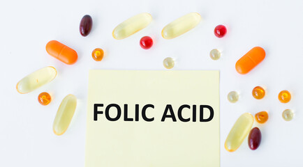 FOLIC ACID text on a yellow sticker on a white background around scattered colorful tablets