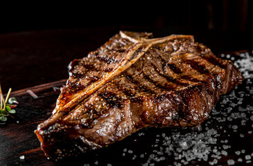 Grilled T-bone Steak on bones on wooden board on dark background