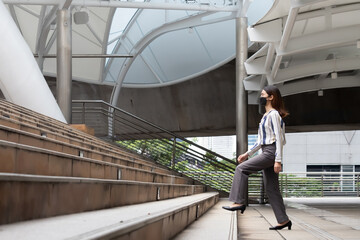 A woman wearing a black mask and a long-sleeved shirt and trousers is walking up the stairs.