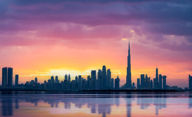 Fototapeta na wymiar Stunning panoramic view of the Dubai skyline during a beautiful sunset with a silky smooth water flowing in the foreground. Dubai, United Arab Emirates.