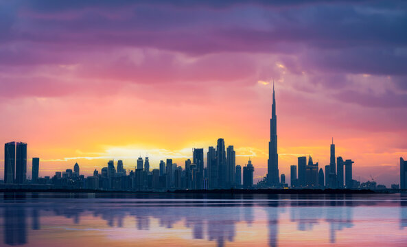Stunning panoramic view of the Dubai skyline during a beautiful sunset with a silky smooth water flowing in the foreground. Dubai, United Arab Emirates.